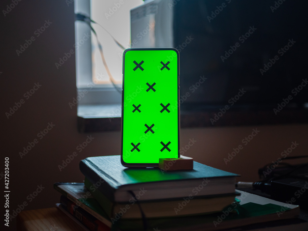 Poster smartphone with a green screen put vertically on notebooks, free space for editing and text