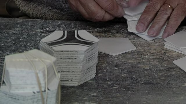 Hands of an Old Worker holding Pieces of Synthetic Leather Pentagons and Hexagons at a Soccer Ball Factory. Close Up. 