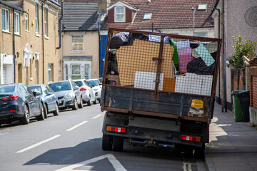 A rubbish collection van filled up with household waste parked on a street