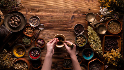 Natural medicine background. Preparation of herbs composition. Assorted dry herbs in bowls and brass mortar on rustic wooden table.
