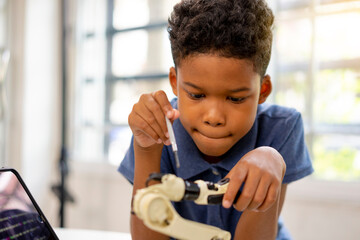An african american boy use screwdriver adjust robot kit.