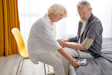 Senior woman and man measuring blood pressure, check health condition