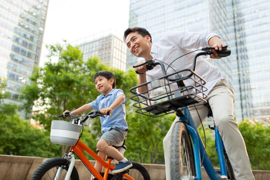 Happy young father and son riding bikes