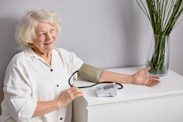 Everyday health check-up. Cheerful senior lady with hypertension measuring blood pressure