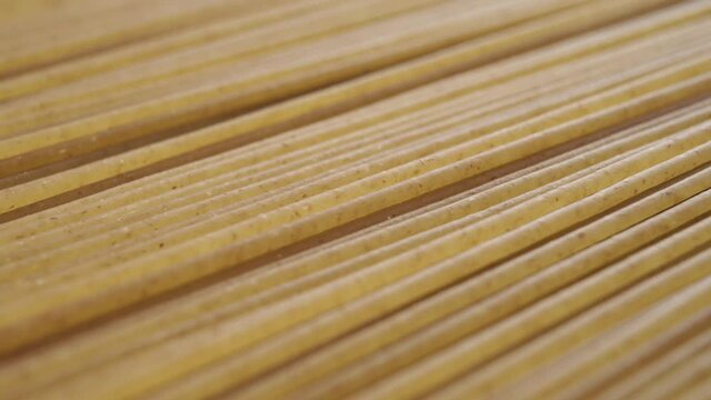 Macro textured surface of raw integral spaghetti stacked in geometric parallel shape. Dolly shot. Traditional Italian Mediterranean cuisine