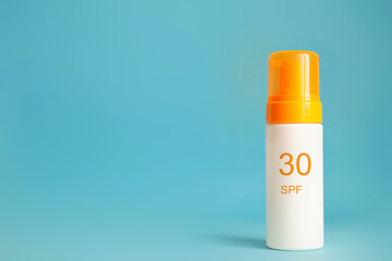 Sunscreen bottle with spf 30 cream or lotion on the aqua blue background with copy space. Sun protection, sunblock, uv cosmetic