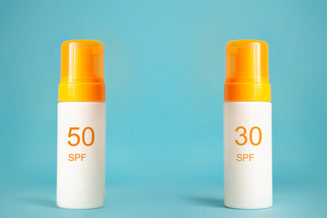 Sunscreen bottles with spf 30 and 50 cream or lotion on the aqua blue background. Sun protection, summer skin moisturizer choosing