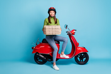 Full length photo portrait of excited woman holding pizza boxes sitting on red scooter isolated on pastel blue colored background