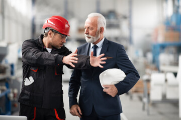 Architect and worker working on project. Colleagues working in factory.
