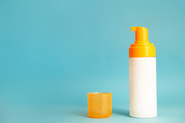 White and yellow after sun cream or lotion on the aqua blue background with copy space. Empty bottle mockup. Spf sun protection, summer skin moisturizer