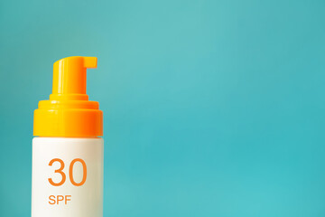 Sunscreen bottle with spf 50 cream or lotion on the aqua blue background with copy space closeup