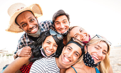 Multiracial friends taking selfie smiling over open face masks - New normal life style friendship...