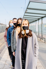 Young diverse unemotional people stand in a row, one after another, in queue waiting for medical help, wearing medical masks on face, outdoor.