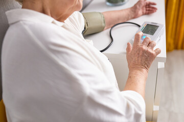 Fototapeta na wymiar Close up top view focus on elderly woman measuring manually blood pressure