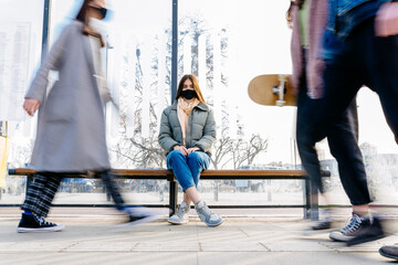 Keeping safe social distance concept. The woman with medical face mask waiting for transport...