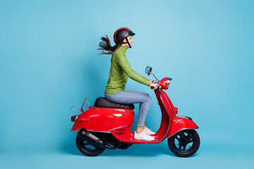 Full length side profile photo portrait of woman in helmet driving red scooter isolated on pastel...