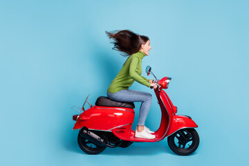 Full length side photo photo portrait of excited girl driving red scooter isolated on pastel blue colored background