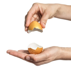 Female hands hold two halves of a broken golden egg on white isolated background.