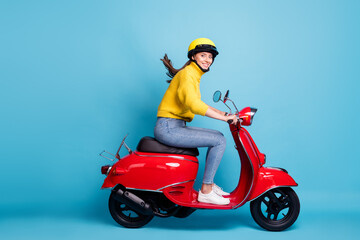 Full length photo portrait of cute girl driving red scooter isolated on pastel blue colored background © deagreez