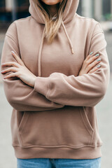 Fasion blonde woman in brown oversize hoodie, glasses and blue jeans, mockup for logo or branding...
