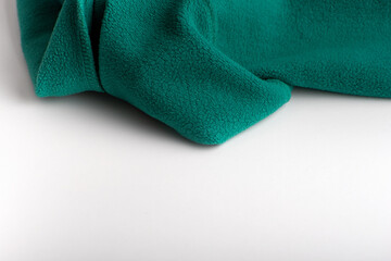 Green cloth on white background. Textile sewing. Fleece fabric folded