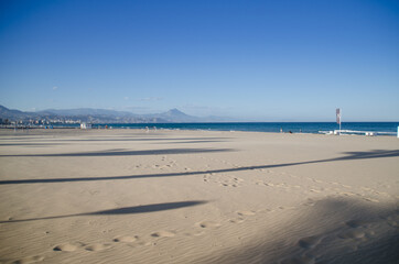 Obraz premium footprints on a clean white sand beach with the sea in the background