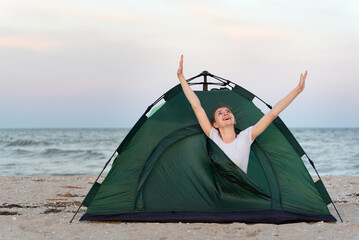 Girl meets the morning in a tent by the sea. Travel, hiking, camping © somemeans
