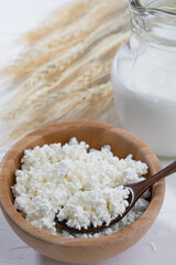 Cottage cheese  and wooden spoon on white background.