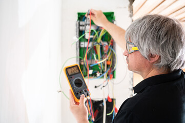 A professional electrician checks the new electrical installation of a house after renovation.