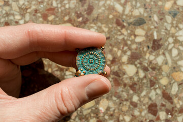 The hand holds an antique pendant. the concept of archaeological excavations.