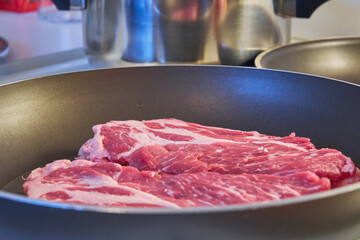 Two pork steaks in a close-up pan.