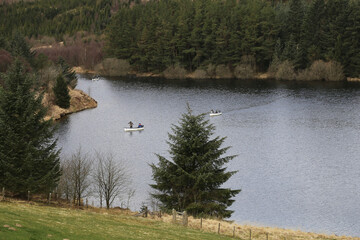 A view down to people fishing in boats in the middle of Llyn Clywedog, Powys, Wales, UK.