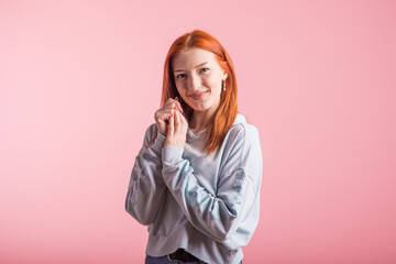 Beautiful young redhead girl in the studio on a pink background