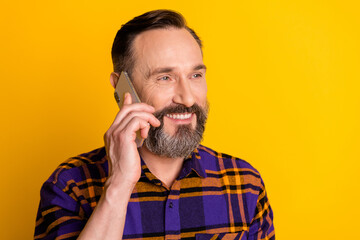 Obraz premium Photo of happy relaxed mature man hold smartphone talk smile enjoy isolated on yellow color background