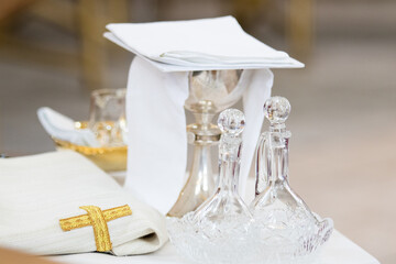 Liturgical objects, sacred vessels: glass altar cruet and liturgical bowl near the altar during the Holy Mass in the Catholic Church