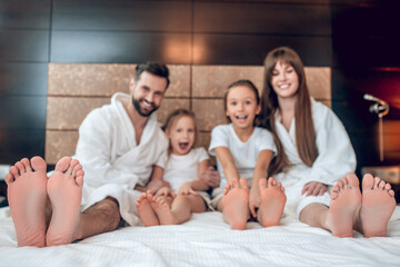 Family in white robes lying in bed and looking happy