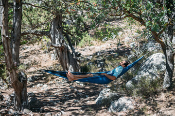 A man in a hammock on a hike in the mountains.