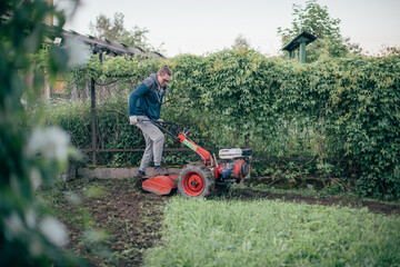 Obraz premium A man works in the garden, plows the soil with a cultivator
