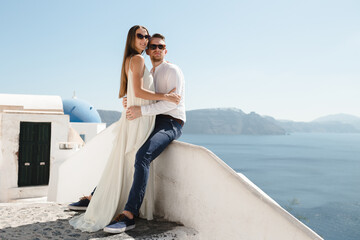 The couple is sitting on the roof in Santorini, hugging and laughing