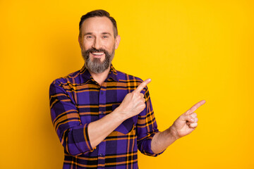 Photo of charming attractive mature man point fingers empty space promoter ad isolated on shine yellow color background