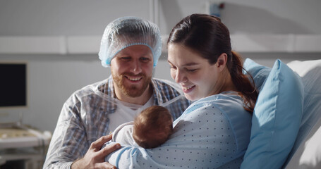 Couple holding newborn baby in maternity hospital after childbirth