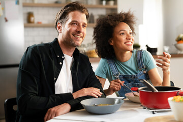 Boyfriend and girlfriend eating lunch with friends at home. Young couple enjoying the company of their friends..