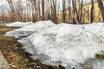 Krasnoyarsk, Russia - April 07, 2021: A pile of melted snow and last year's dried leaves in the park in spring