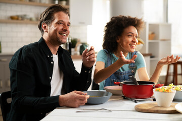 Boyfriend and girlfriend eating lunch with friends at home. Young couple enjoying the company of their friends..