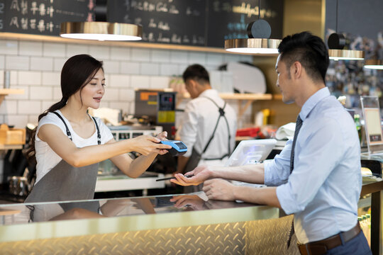 Businessman paying with smart phone in caf��