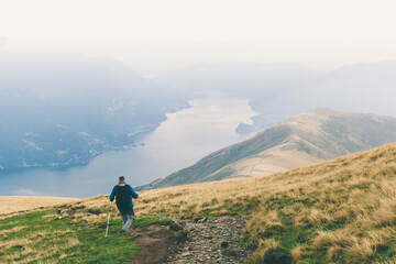 Man is highting with fog misty view mountains and lake landscape. Summer vacations outdoor. Trekking scene on Lake Como alps. Solo tourism, escape, alone traveller. Scenic photo, copy space