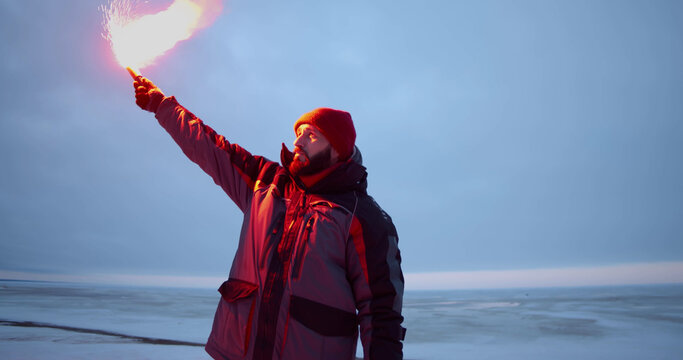 Fisherman lightning signal fire on frozen lake in winter