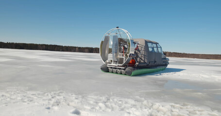 Rescue team in hovercraft and sailing across frozen lake
