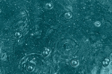 blue background puddle of rain / raindrops, circles on a puddle, bubbles in the water, the weather is autumn