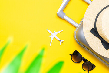 Summer holidays background. Womens accessories traveler: suitcase, white plane, sunglasses on yellow background with empty space for text. Exotic tropical beach with copy space.